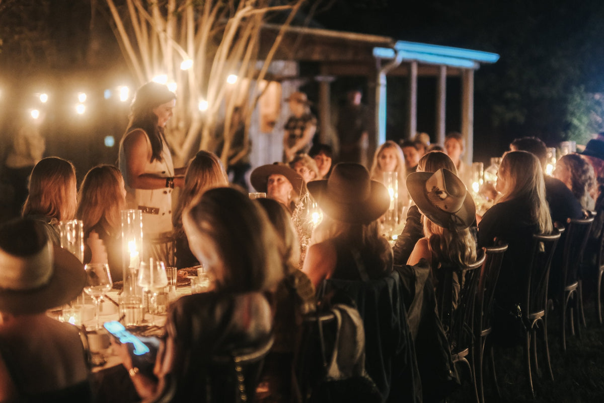 Guests gathered around a candlelit table under string lights at the FEED x Katie Kime dinner in Round Top