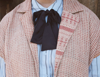 Pink woven vest with a black bow tie and striped shirt
