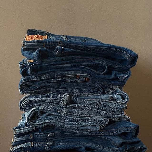 Stack of vintage Levi's jeans folded on a wooden surface at Round Top Texas antiques show