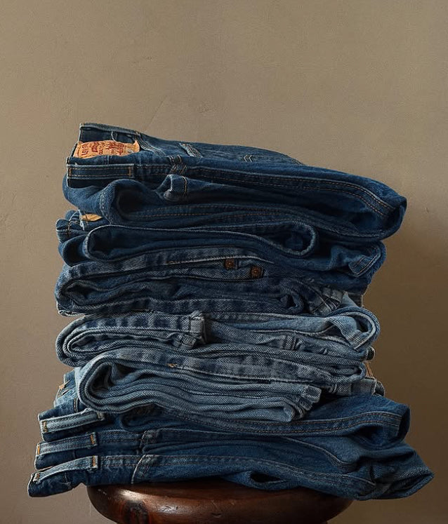 Stack of vintage Levi's jeans folded on a wooden surface at Round Top Texas antiques show